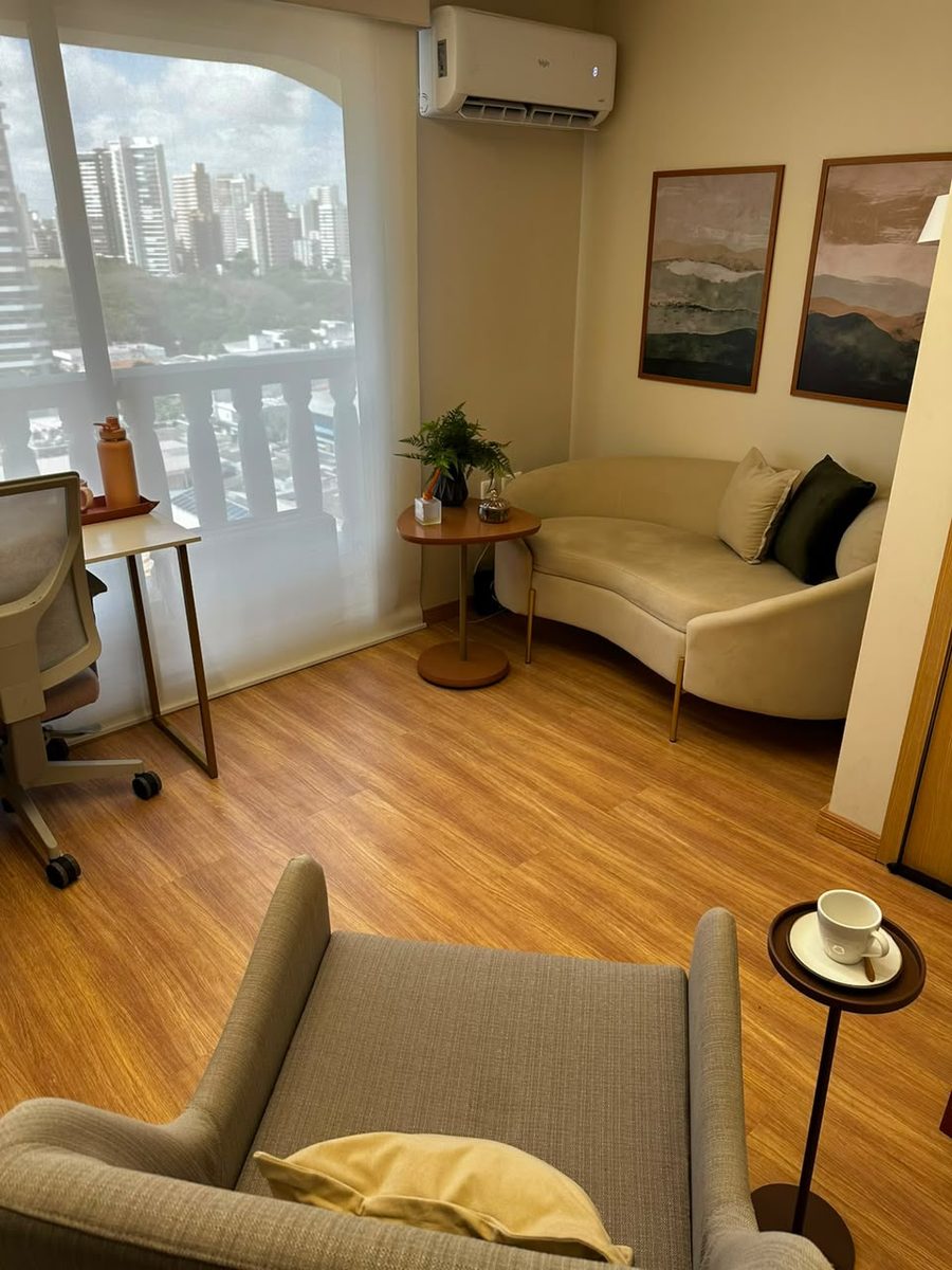 Sala de atendimento com poltrona, sofá e janela com vista da cidade